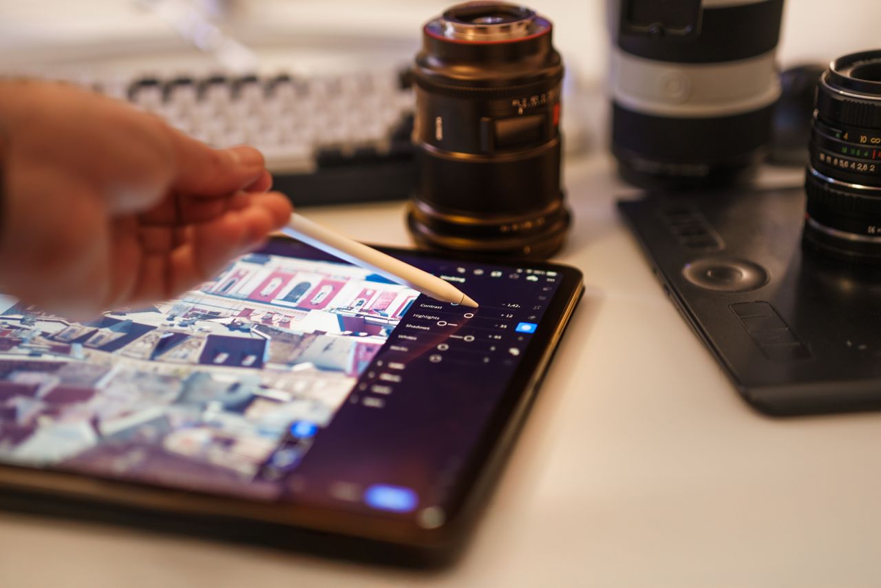 Une vue détaillée d’un environnement professionnel de retouche photo avec une tablette et des objectifs.